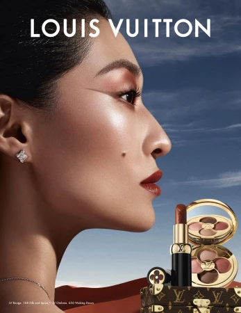Close-up profile portrait of a model with dramatic makeup against a desert landscape and blue sky background with Louis Vuitton text