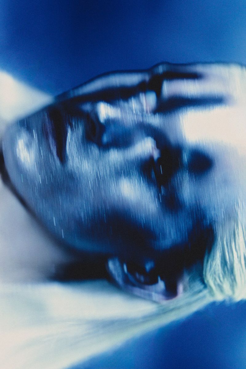Abstract portrait of a person with a blurred face and light hair, rendered in shades of blue and white with a dreamy, ethereal quality.