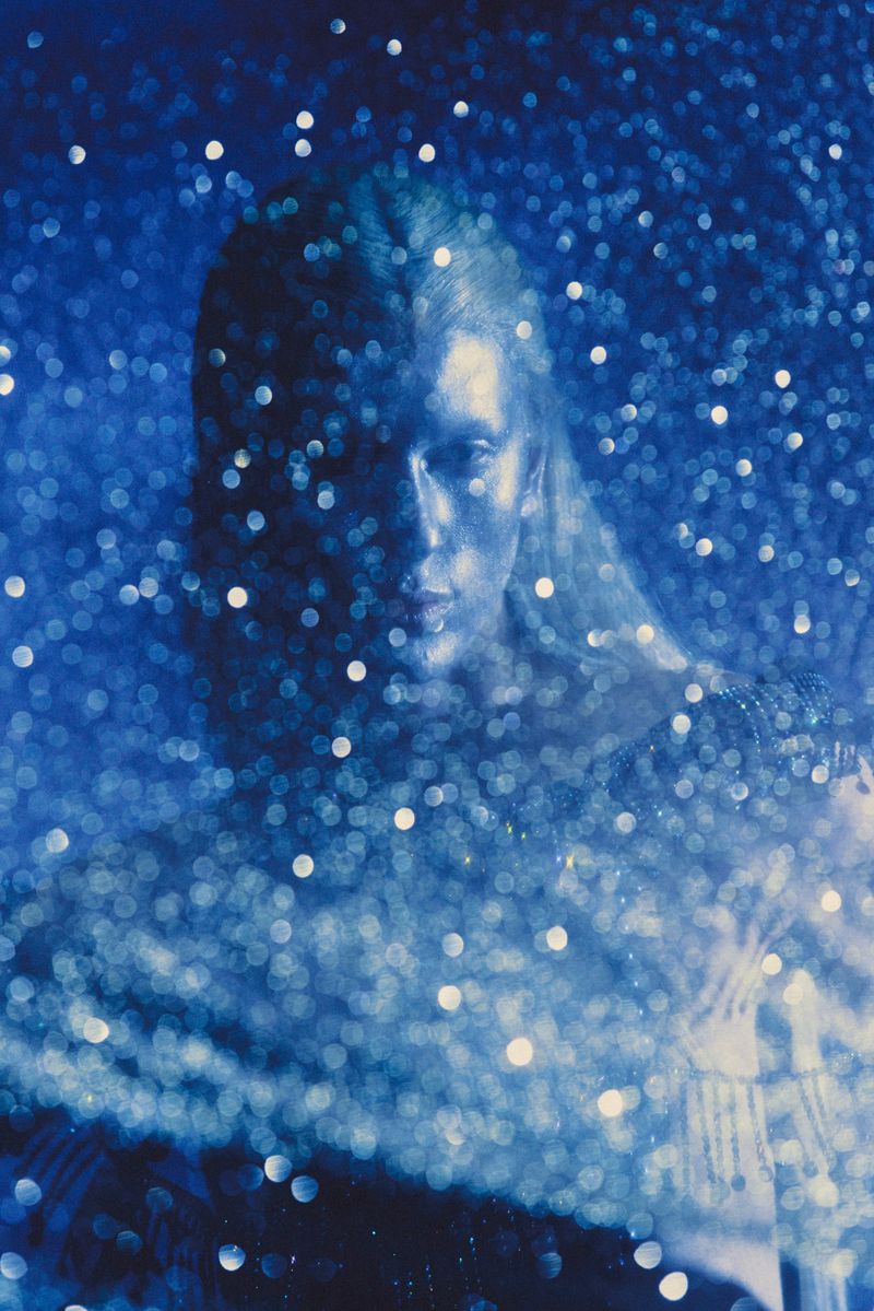 Woman portrait in blue tones, surrounded by bokeh effects. The artistic image highlights the model's serene expression and ethereal aesthetic.