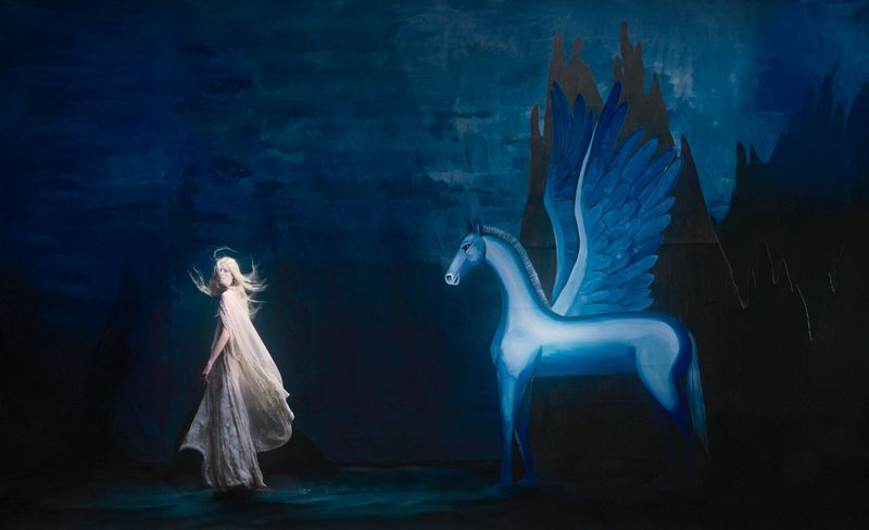 Dreamy oil painting of a woman in a flowing dress with a halo gazing at a winged horse against a dark blue, castle-dotted background.