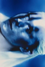 Close-up portrait of a model with motion blur against a moody blue background for Elle Brasil