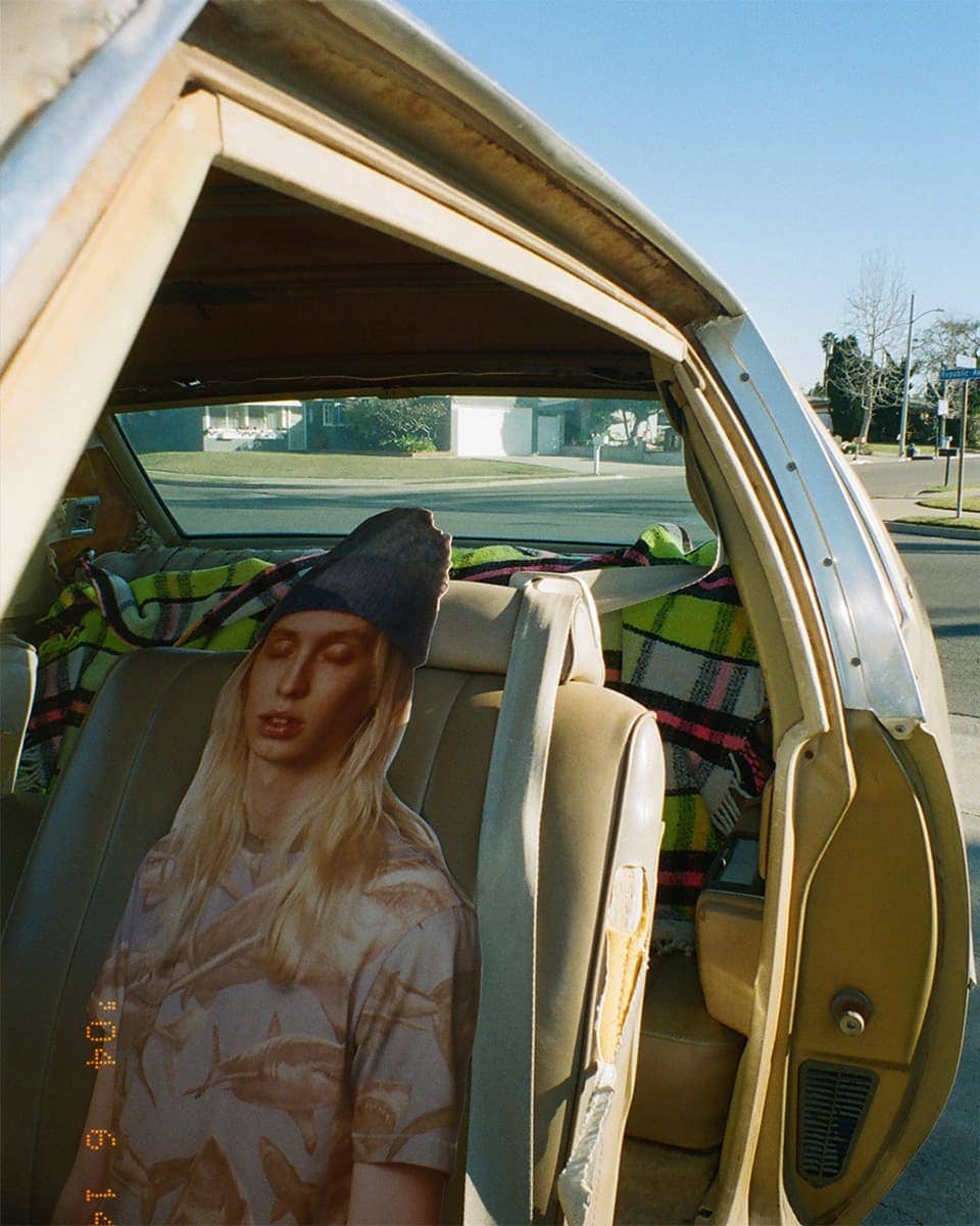 Cardboard cutout of a person with long blonde hair and a beanie placed on a car seat
