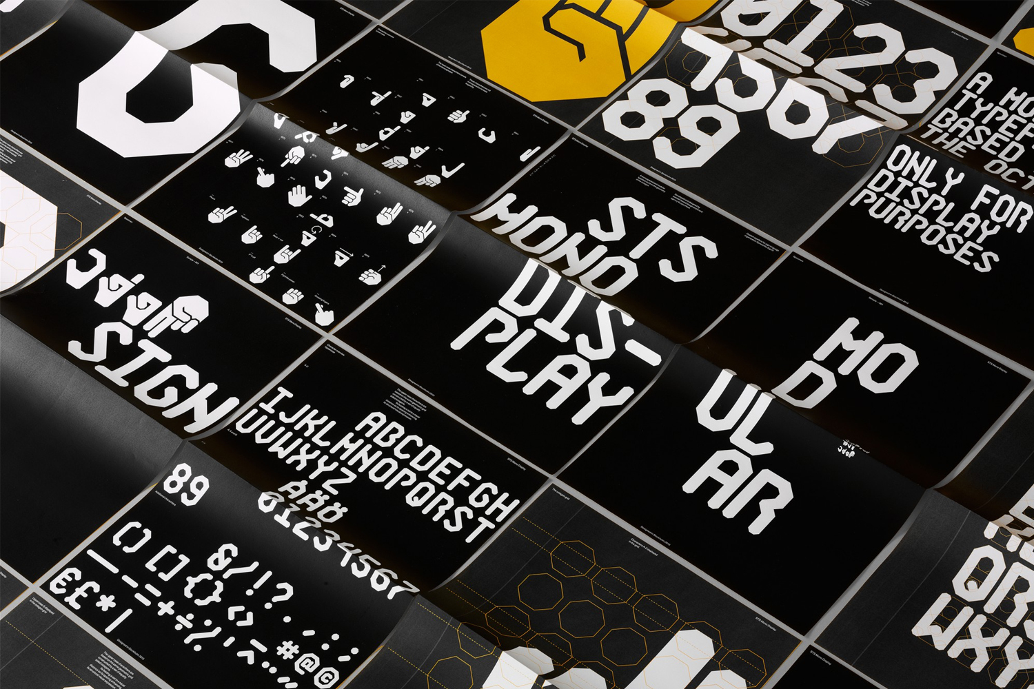 Close-up perspective view of black posters displaying bold white geometric typography and graphic iconography.