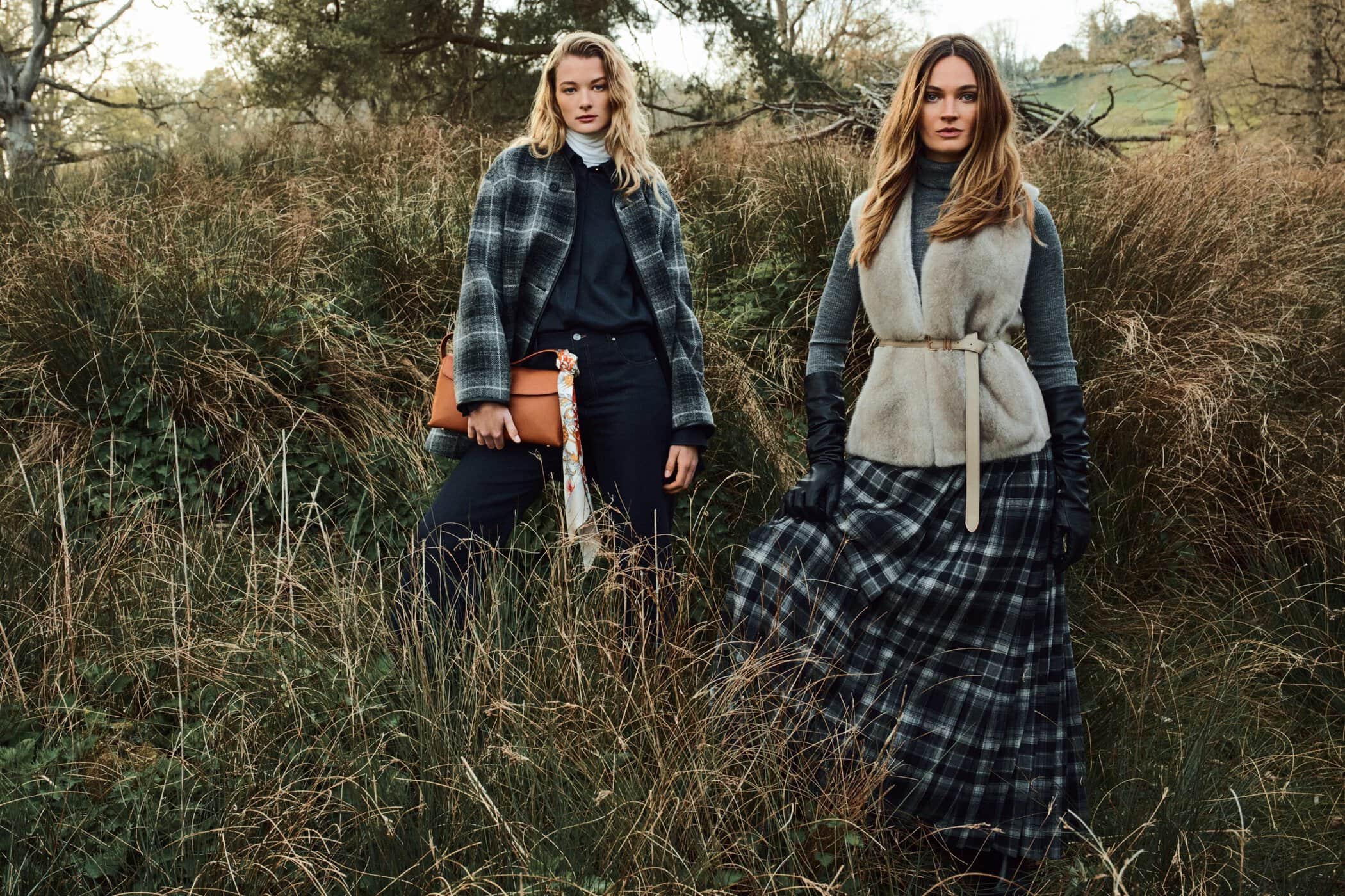 Two female models posing in tall grass wearing plaid outerwear and knitwear for PORTS Fall 2025 campaign.