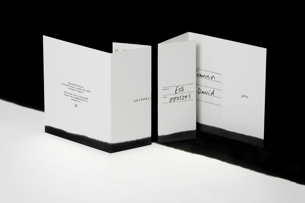 Folded paper cards with printed text and handwritten details set against a contrasting black and white background.