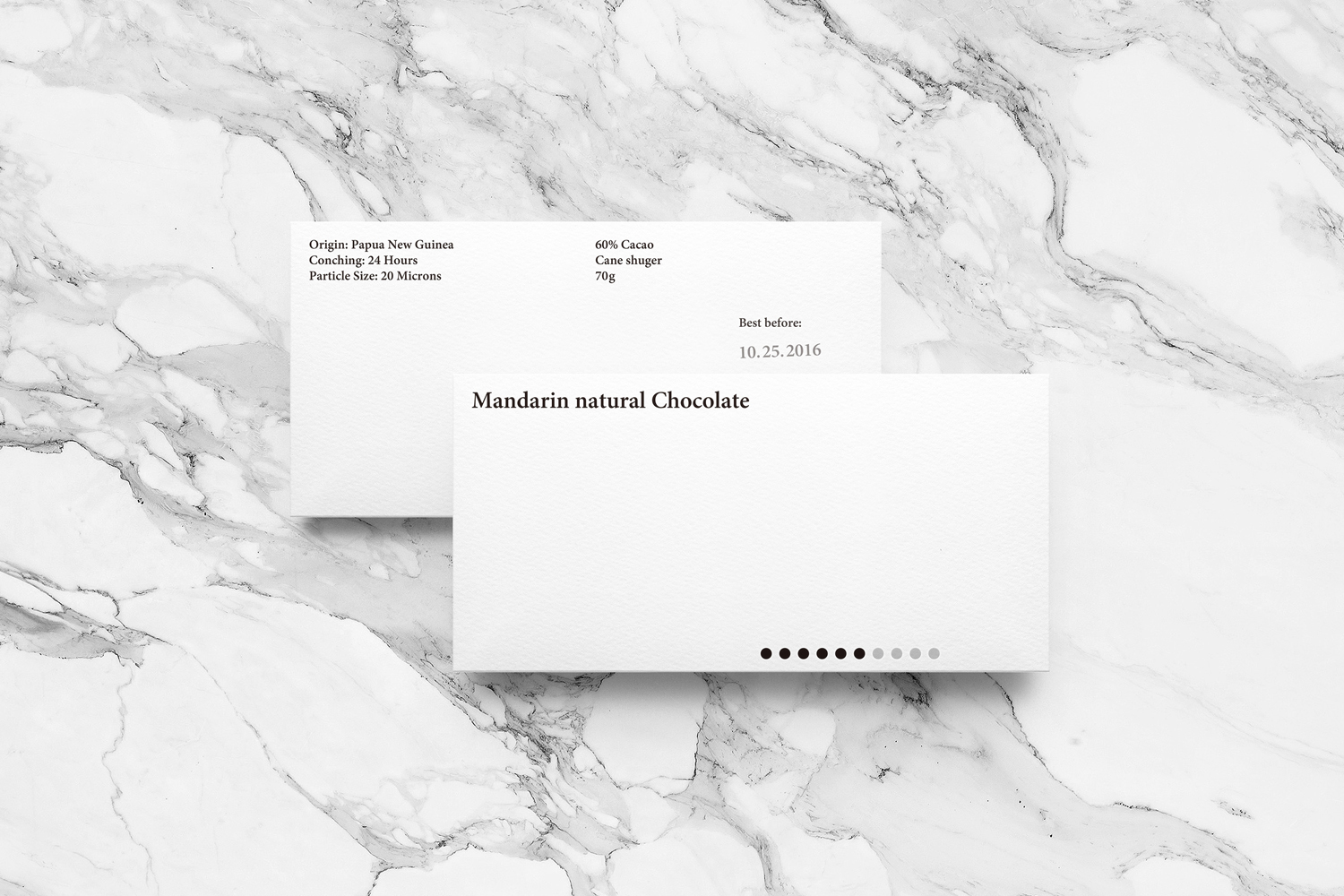 Two white rectangular product packaging cards resting on a white marble surface with grey veining patterns