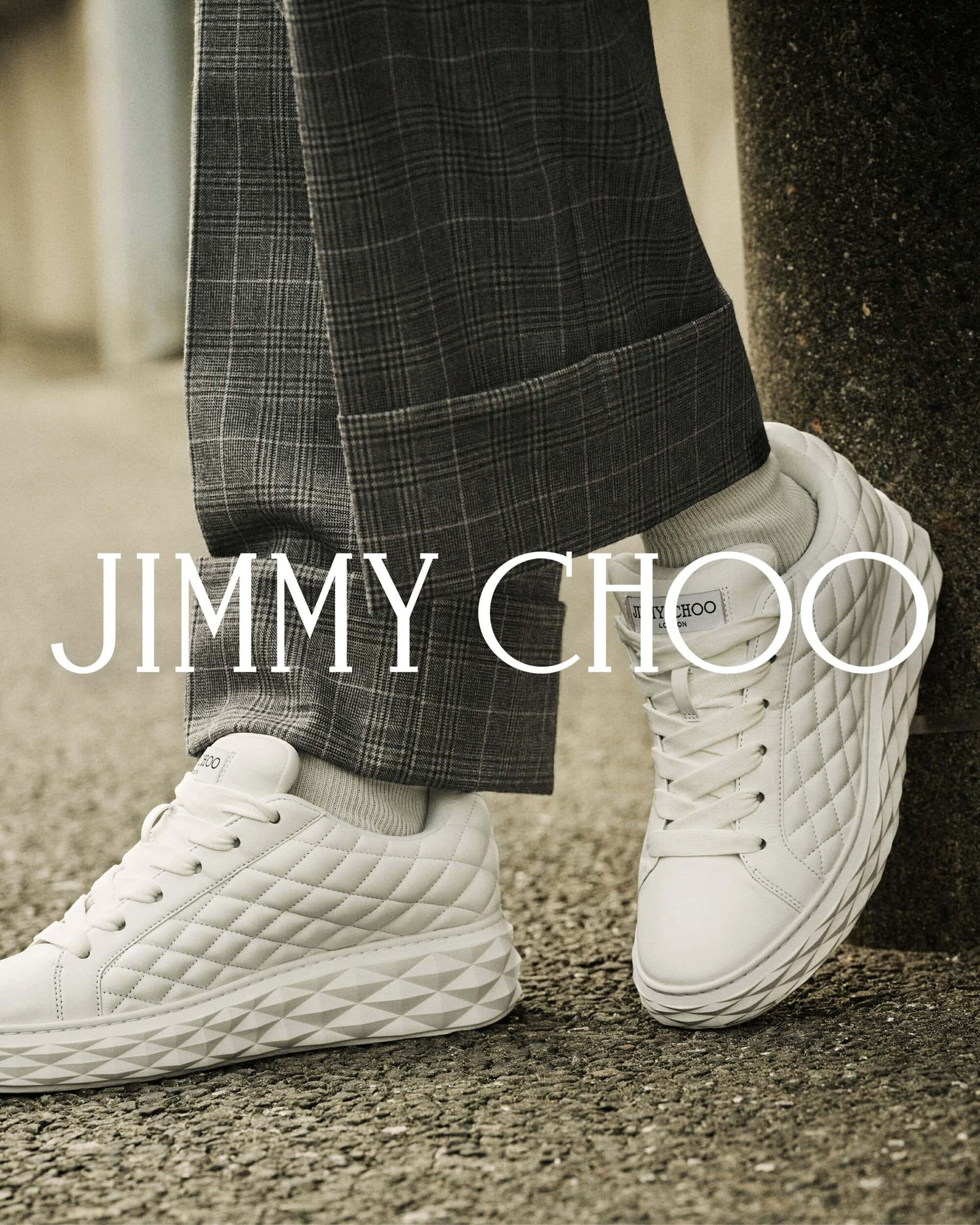 Close-up shot of white quilted leather sneakers worn with plaid trousers and white socks for Jimmy Choo.