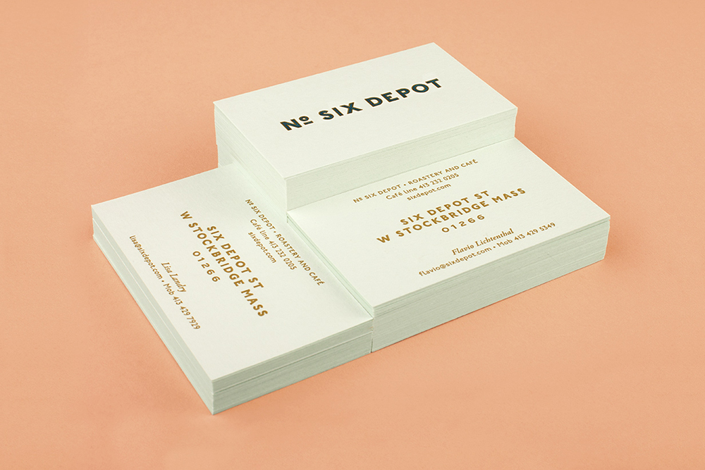 Stacks of white business cards with bold typography on a peach colored background surface.