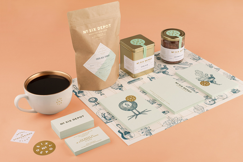 Coffee packaging, tin, jar, business cards, and a cup of black coffee arranged on a peach surface.