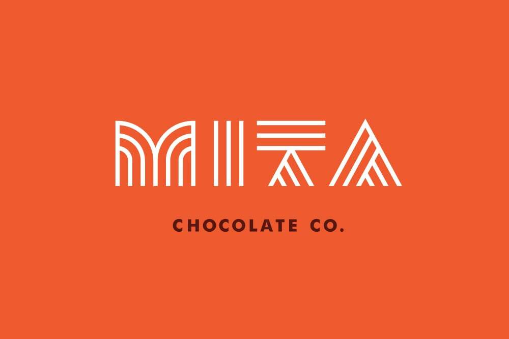 White geometric brand logo spelling MITA with smaller text reading CHOCOLATE CO. set against an orange background.
