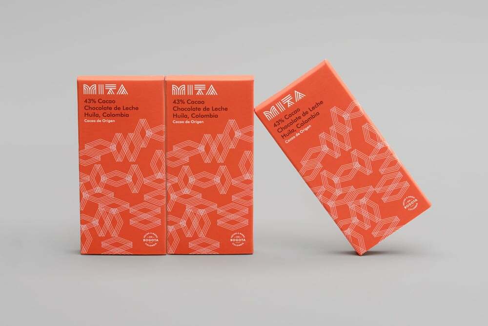 Three orange Mita Chocolate Co. packaging boxes displayed on a neutral grey background surface