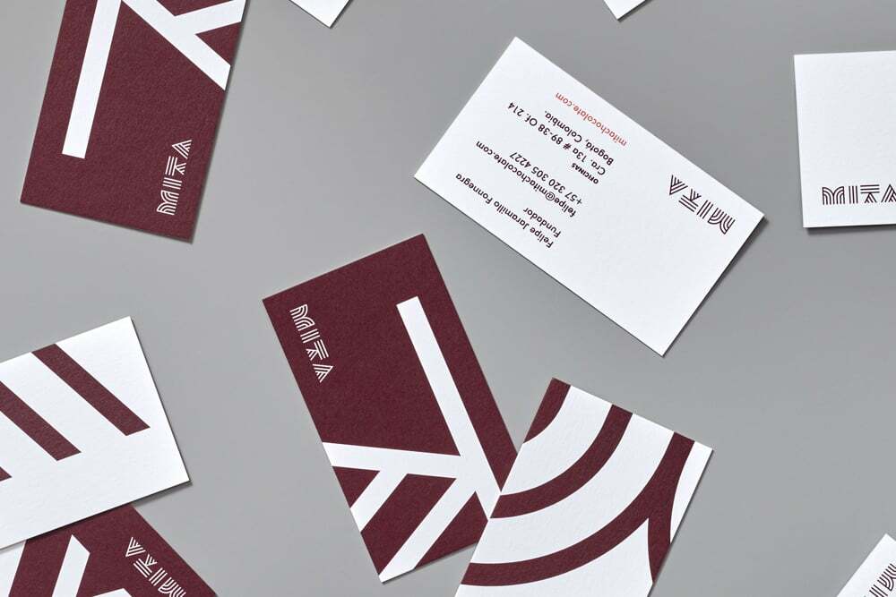 Flat lay of Mita Chocolate Co business cards in burgundy and white on a grey background