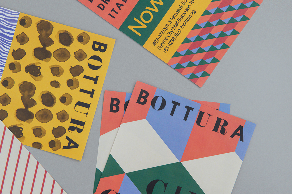 Flat lay of colorful branded collateral materials with geometric patterns and typography on a grey background