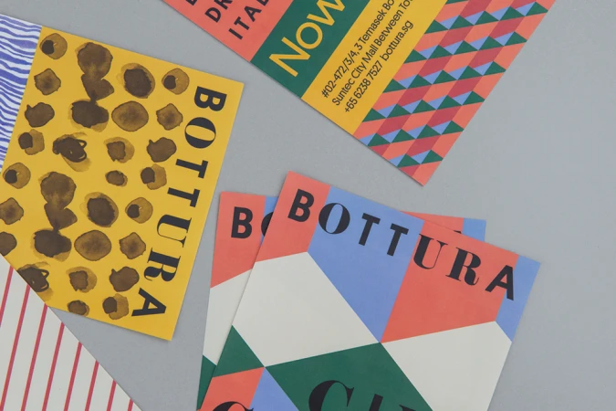 Flat lay of colorful branded collateral materials with geometric patterns and typography on a grey background