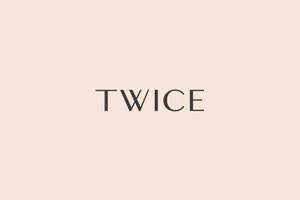 Twice brand identity typography featuring dark grey serif letters centered against a pale peach background.
