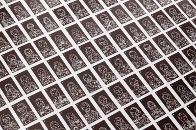 An array of dark rectangular cards featuring intricate white line art character illustrations laid out on a white surface.