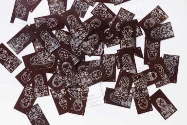 Scattered brown business cards featuring white line art portraits and illustrated icons against a white background