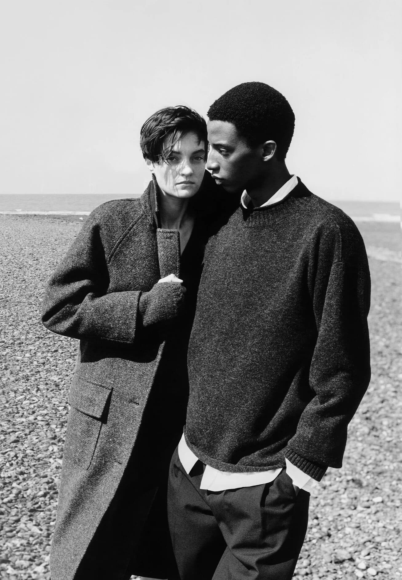 Two models standing on a pebbled beach wearing heavy knitwear and outerwear for Margaret Howell.