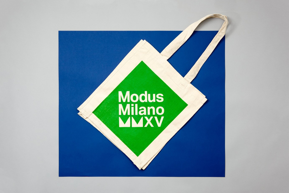 Canvas tote bag with a green square and Modus Milano text placed over a blue square against a grey background