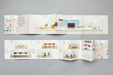Two folded accordion brochures showing graphic design and workspace photography displayed on a plain grey background