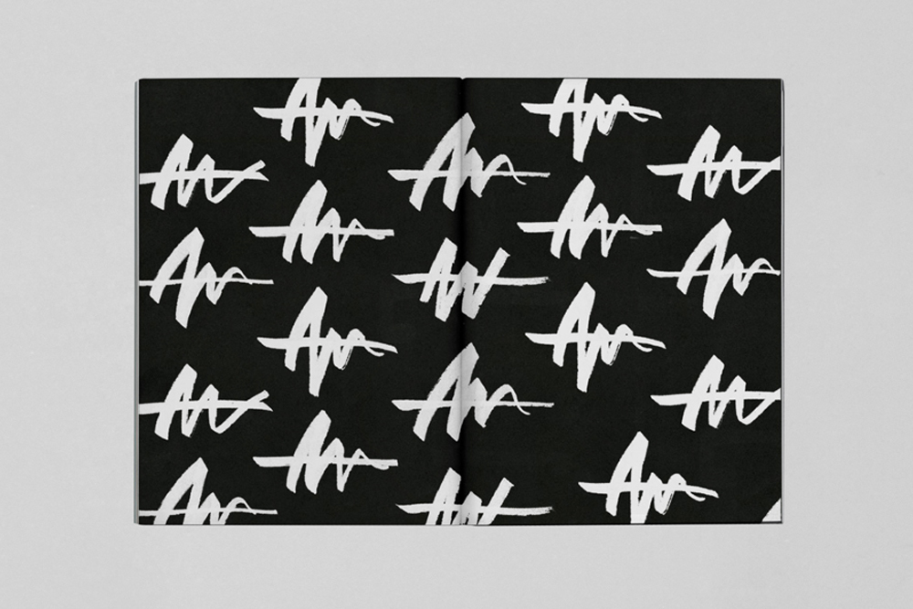 Open book layout featuring a repeating white brushstroke pattern on a black background set against a neutral grey surface.