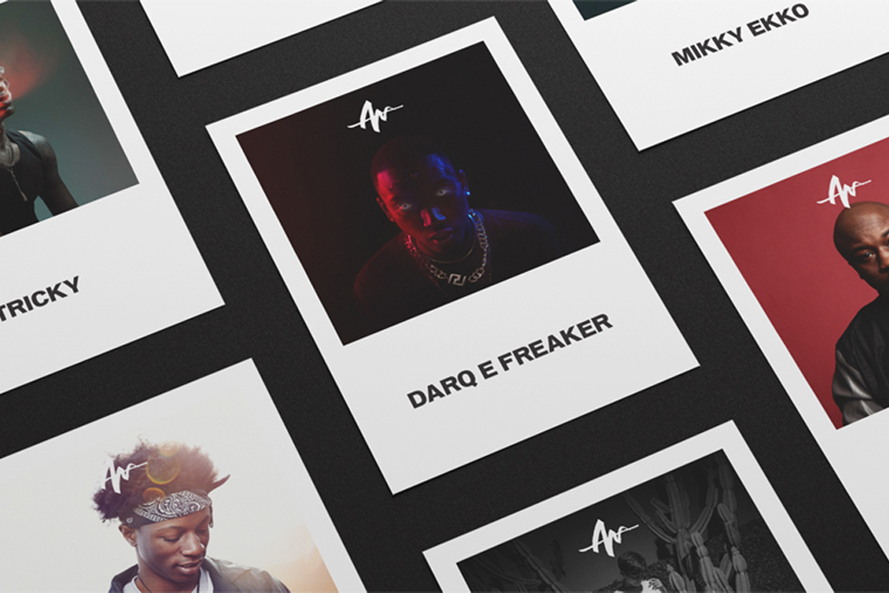 Multiple square printed cards featuring artist portraits and names arranged on a dark textured surface