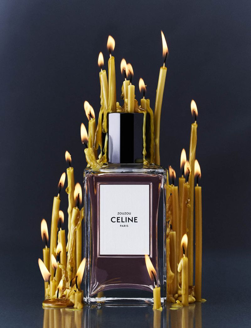 Perfume bottle surrounded by lit candles, creating a warm, inviting ambiance with a high-end luxury feel against a dark background.