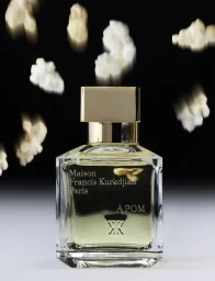 A perfume bottle set against a black background with motion-blurred white pieces floating above it.