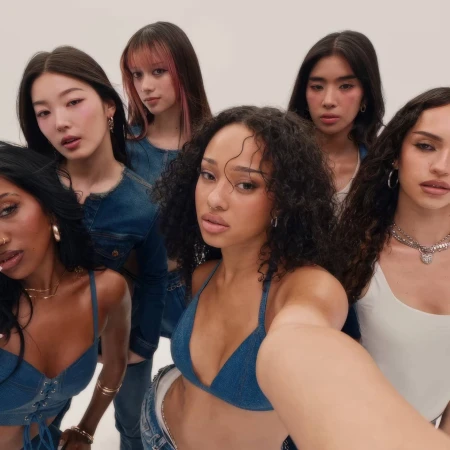 Group of six young women posing together in a studio setting against a seamless white background for a Gap campaign.