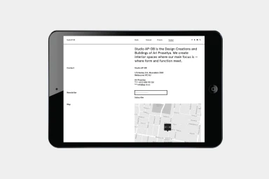 A black tablet displaying the contact page of the AP-DB studio website on a light grey background.
