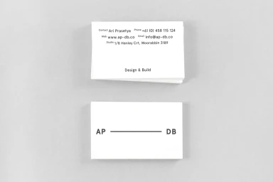 Two white business cards with minimalist black typography displayed on a neutral grey background.