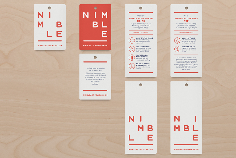 Collection of white and red branded swing tags and product labels laid out on a light wood surface