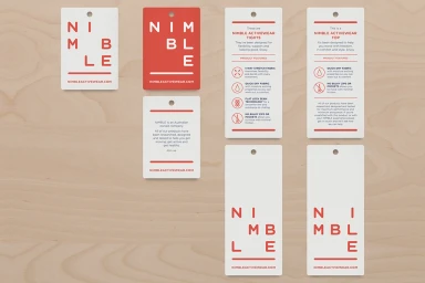 Collection of white and red branded swing tags and product labels laid out on a light wood surface