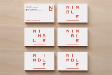 Six white business cards with red typography arranged neatly on a light wood grain surface.