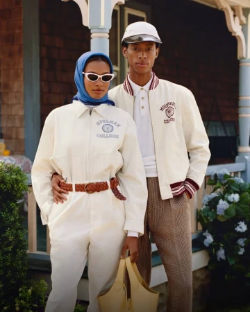 Two models wearing collegiate cream outerwear posing together on a porch in an editorial campaign