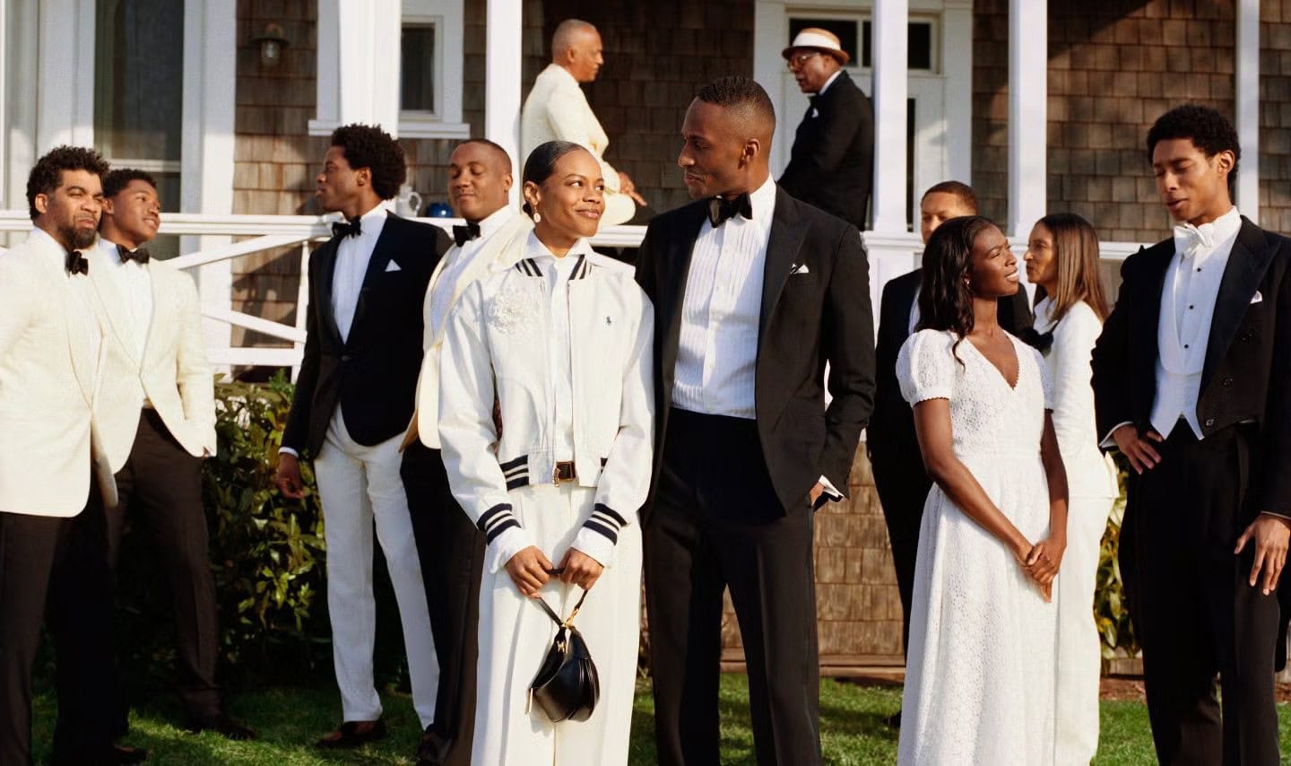 Group of people in formal attire and tuxedos gathered outside a traditional wooden house for Polo Ralph Lauren Oak Bluffs campaign.