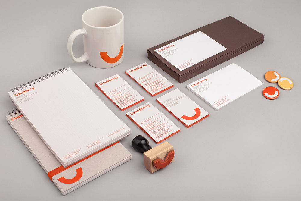 Cloudberry brand identity stationery mockup featuring a white mug, notebooks, business cards, rubber stamp, and pins on a grey background
