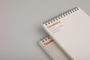 Two spiral-bound dot grid notebooks stacked on a plain grey surface with Cloudberry branding printed on the cover