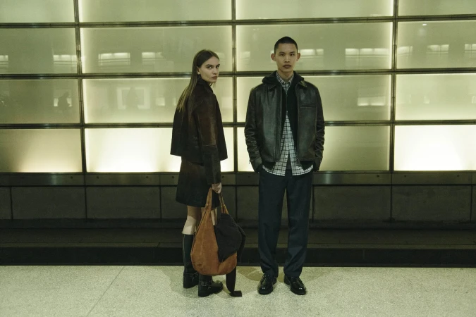 Two models standing against an illuminated gridded wall in an urban setting for Samsoe Samsoe fall 2025 ad campaign.