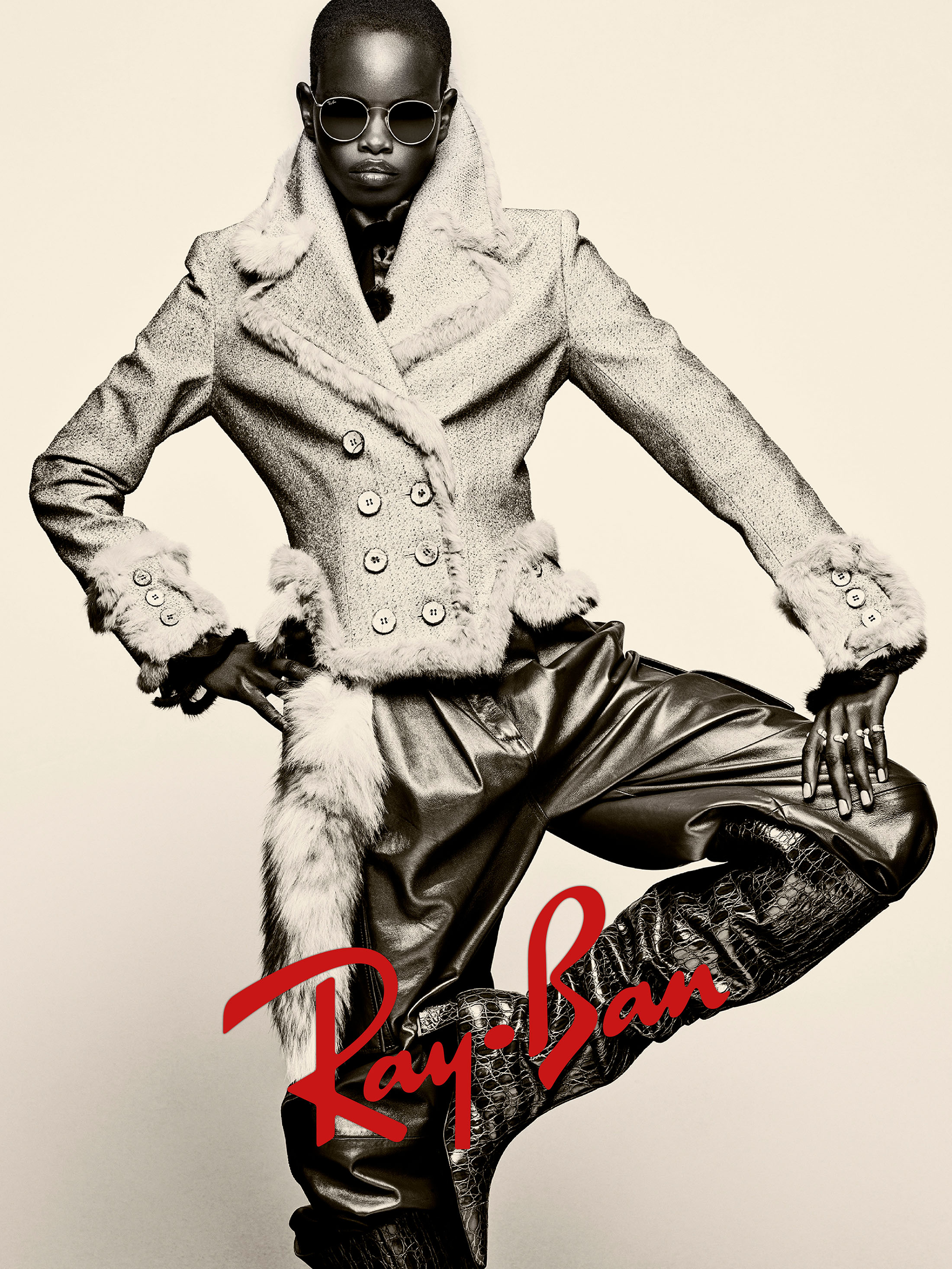 Model wearing round sunglasses and a double-breasted textured coat against a plain background for Ray-Ban campaign