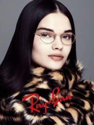 Model wearing gold-framed glasses and a patterned faux-fur coat against a grey background for Ray-Ban