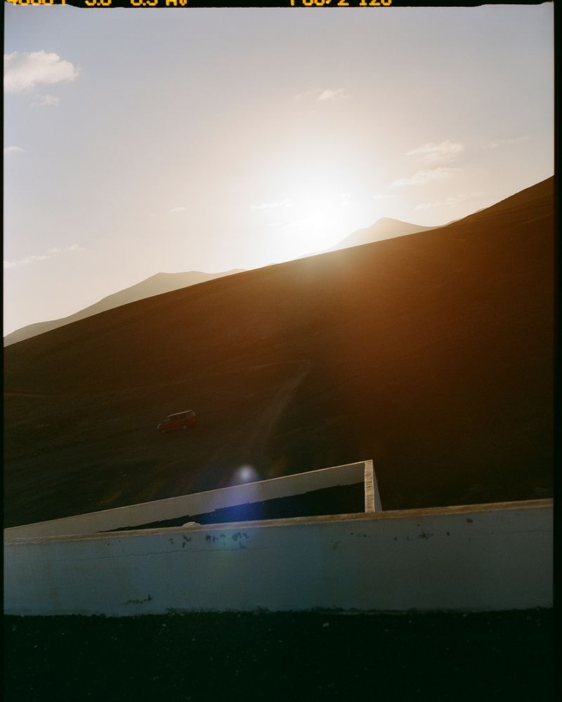 Tranquil landscape featuring a hillside with sun and sky, complemented by a concrete structure in the foreground, creating a serene scene.