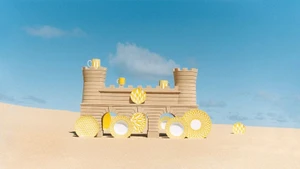 Sandcastle structure with yellow patterned plates and mugs set against sandy beach and clear blue sky.