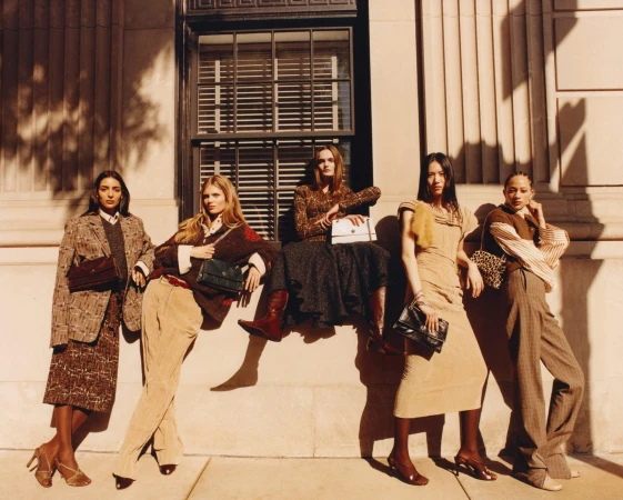 Group of five female models posing against a stone building exterior with tall windows for Tory Burch Fall 2025 campaign