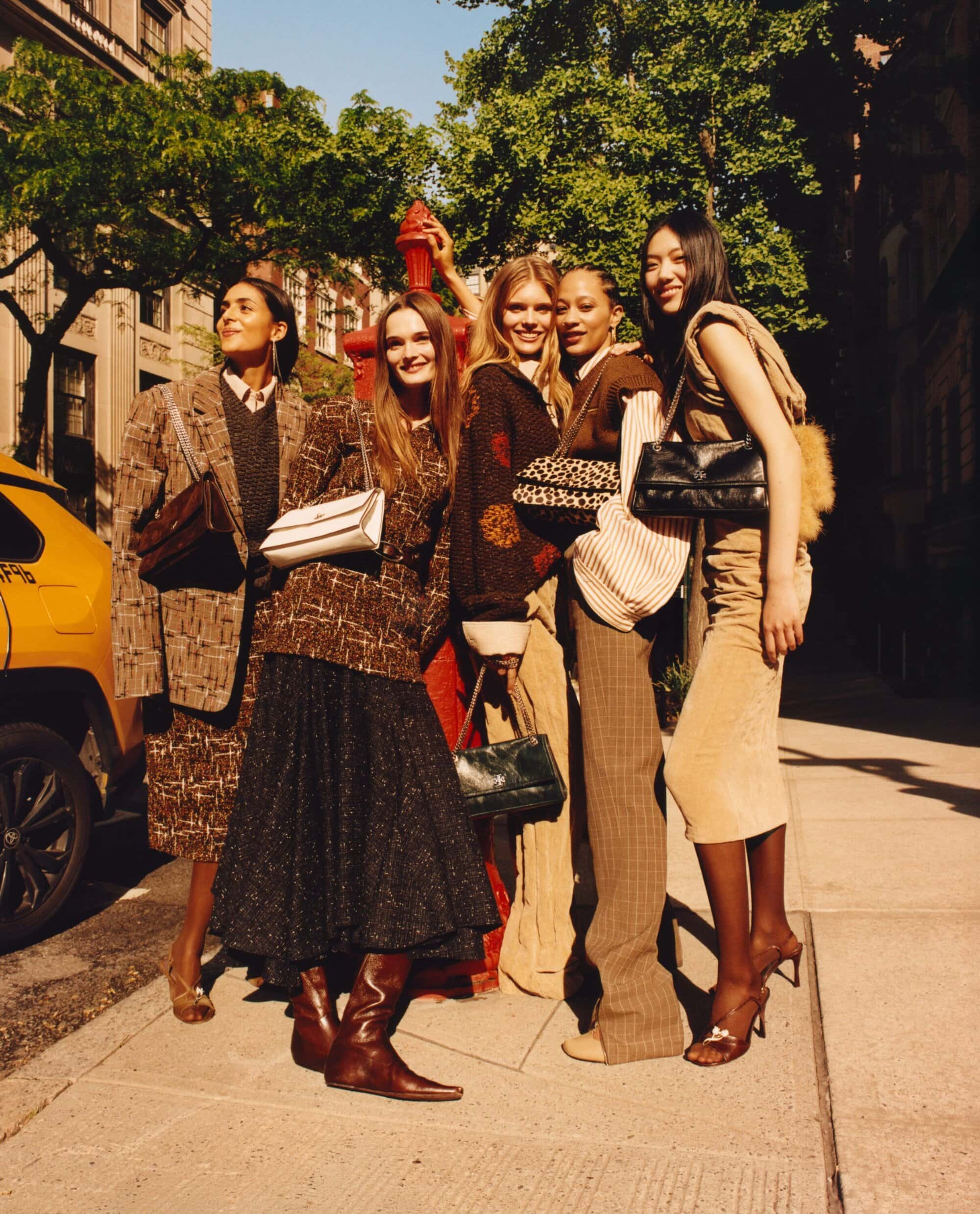 Five models posing together on a New York City street during the Tory Burch Fall 2025 ad campaign, photographed by Jamie Hawkesworth.