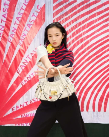 Model holding a white leather handbag against a red and white striped background with repeated text for Marc Jacobs Fall 2025 campaign