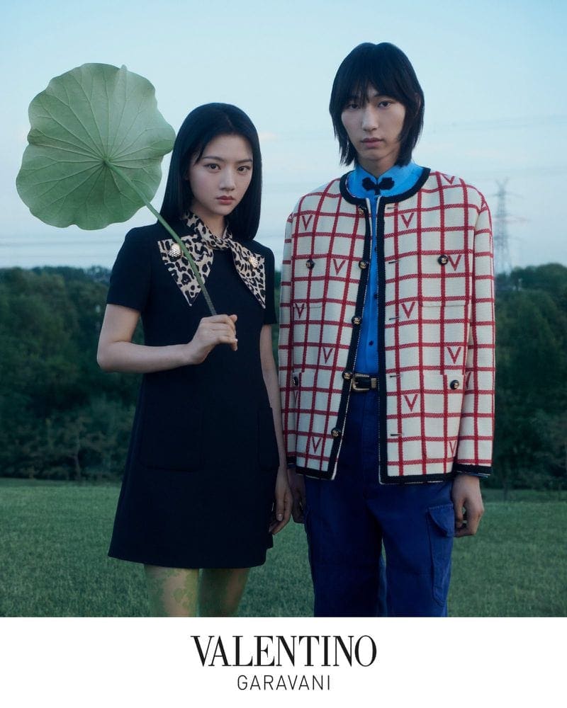 Two models standing outdoors in a field holding a large lotus leaf for Valentino Chinese Valentine's Day ad campaign.