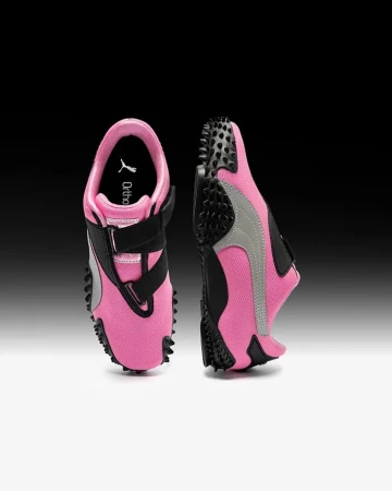 Product shot of Puma Mostro sneakers in pink and black viewed from top and side against a gradient background.