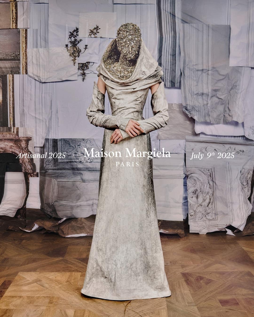 Model wearing a heavily embellished beaded mask and draped grey gown standing against a collage backdrop