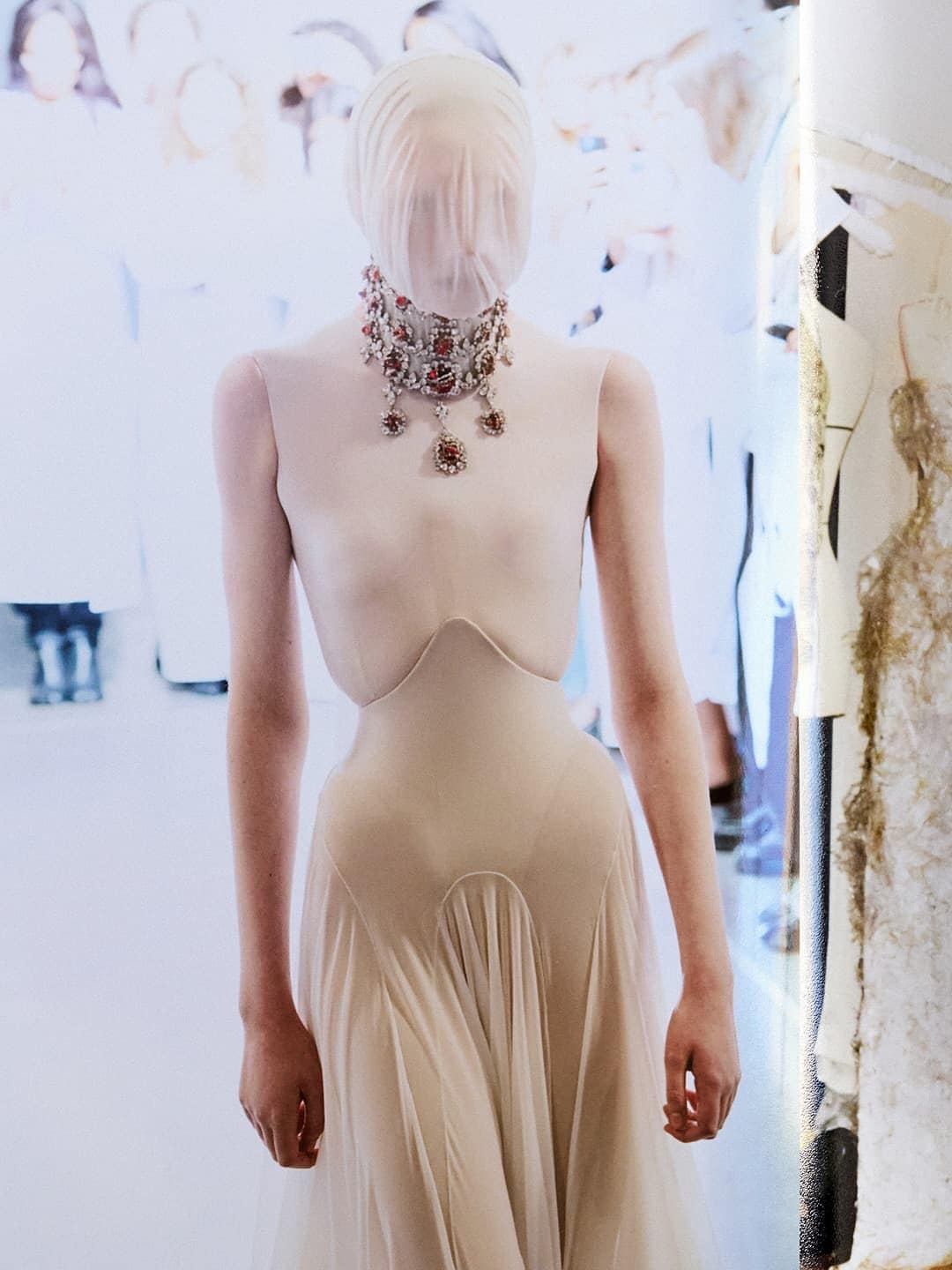Model wearing a sheer face veil, heavy jewelled choker, and structured neutral dress for Maison Margiela Artisanal campaign